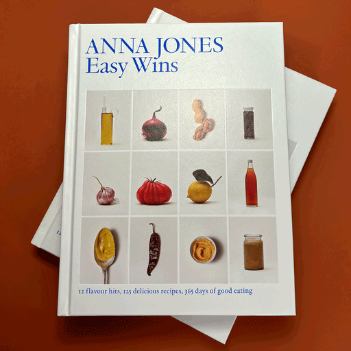 two white books on top of eachother in front of a burnt orange background. On the front cover it says "Easy Wins" by Anna Jones and has  12 images