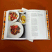 cookbook open on its flat showing recipe in front of a brunt orange background