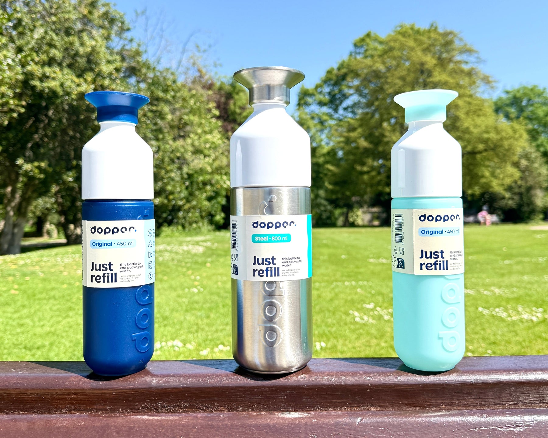 Dopper reusable water bottles displayed in a sunny park.