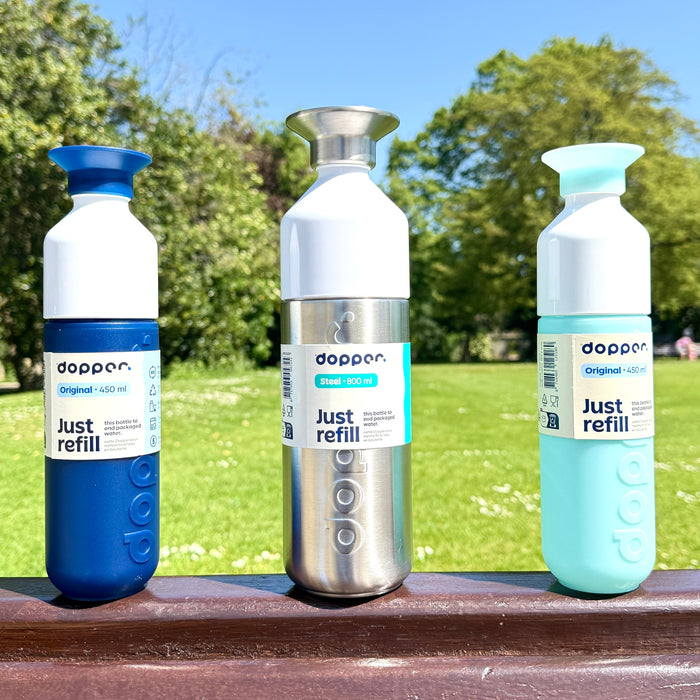 Dopper reusable water bottles displayed in a sunny park.