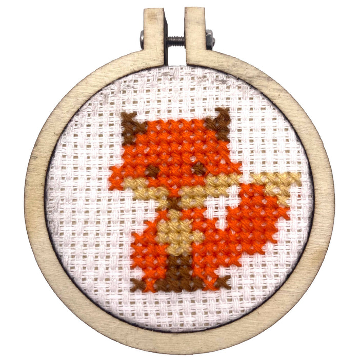 Cross-stitched fox design in a wooden hoop on a white background