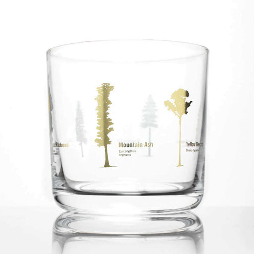 glass whiskey tumbler with tree silhouette in gold foil around outside of glass