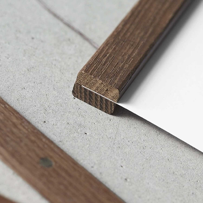 Close-up of a wooden strip holding a sheet of white paper on a concrete surface