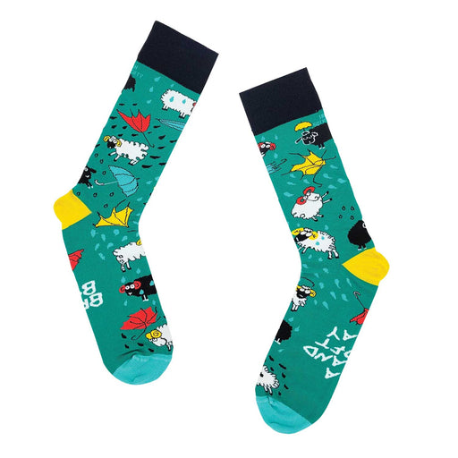 pair of green socks with black band and yellow heal. Socks have pattern of sheep , broken umbrellas and raindrops