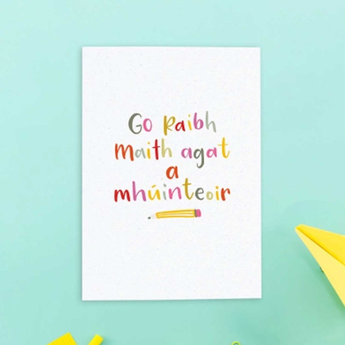irish text greeting card which reads in English, thank you teacher. The letters are bright and colourful with a yellow pencil with pink rubber tip underneath the text