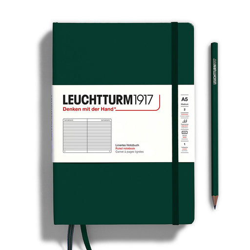 forest green leuchtturm notebook with green elastic band, two green page ribbons and white paper band across cover. Green  pencil to right