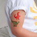 Colorful dinosaur tattoos on a child's arm with a white shirt.