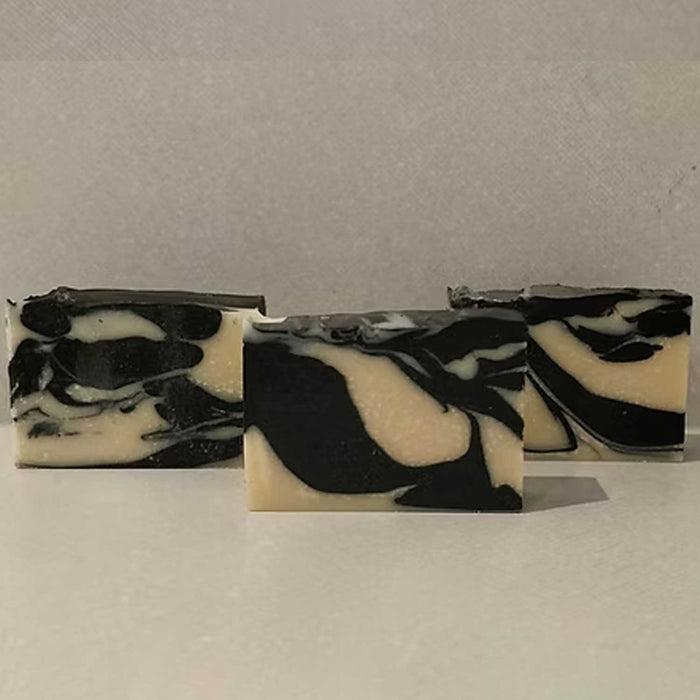 3 bars of black and white swirl patterned soap in 
front of a grey background