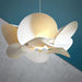 cream white abstract floral bloom shaped light shade hanging from a white wire against a blue and concrete grey background