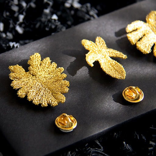 3 golden thread leaf brooches on black board with gold pin clasps