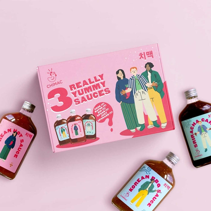 3 glass bottles of sauce with pink box in centre