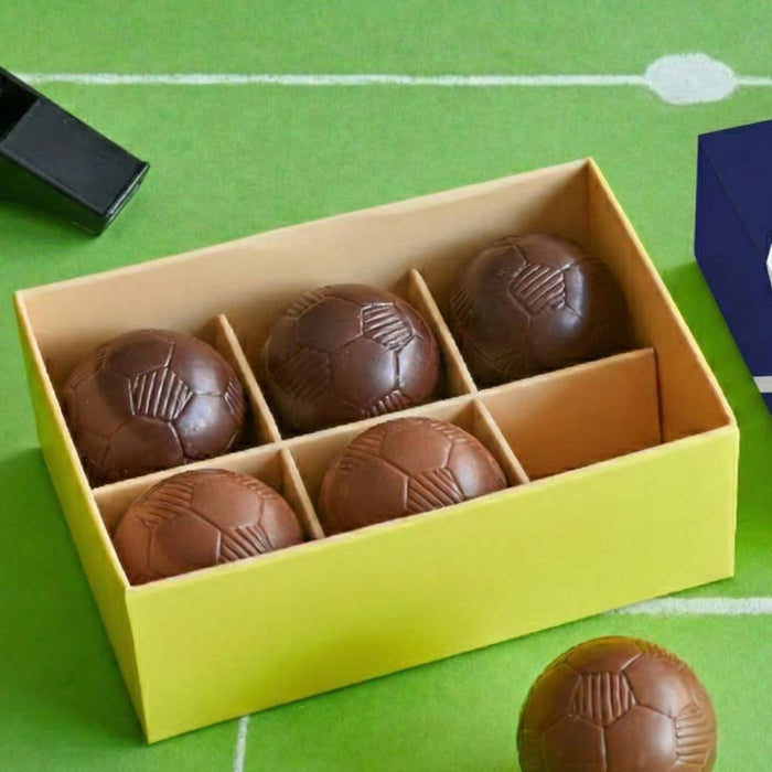 Box of chocolate footballs  on a green field background