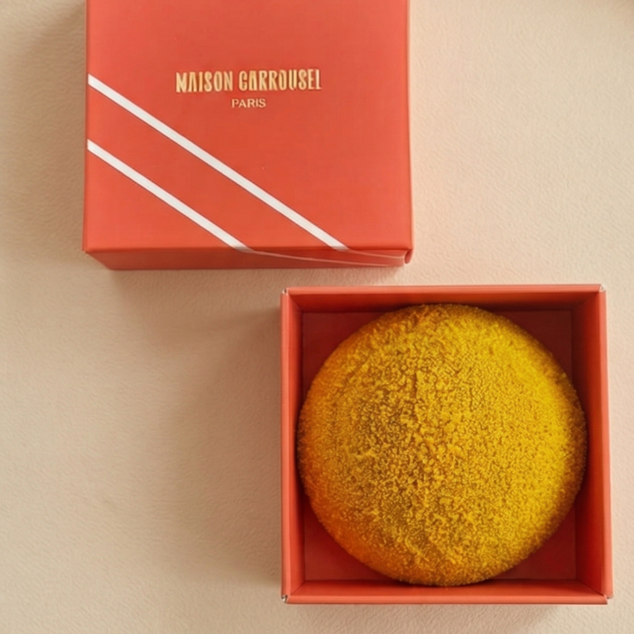 Chocolate Tennis Ball in an orange box with 'Maison Carrousel' branding on a beige background
