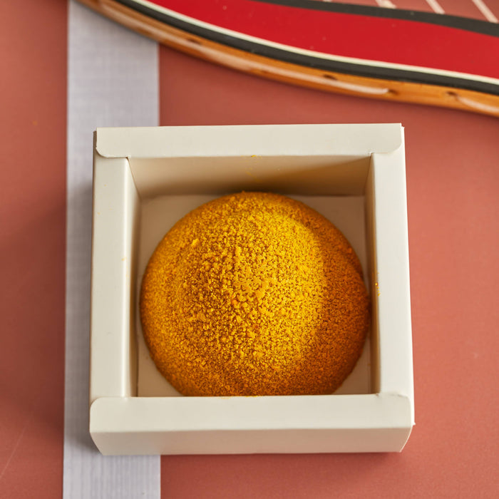 Chocolate tennis ball in box with tennis racket against terracotta background
