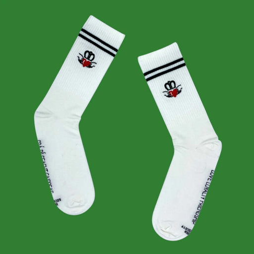 pair of white socks with claddagh ring emblem and two black stripes near ankle. On a green bakcground