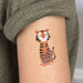 Tattoo of a tiger on a person's arm with a neutral background