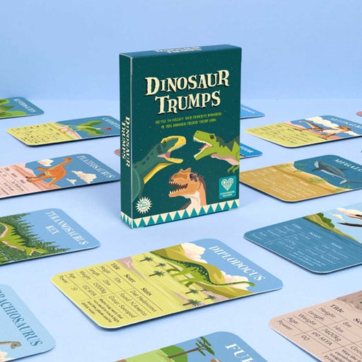 pack of dinosaur trump cards. Green box of cards against blue background with open cards lying around teh pack
