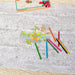 Coloring poster with dinosaur illustrations and colored pencils on a textured surface.