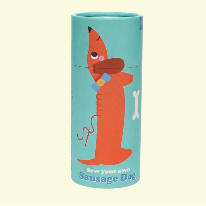 Cylindrical craft kit packaging with a sausage dog illustration on a light yellow background