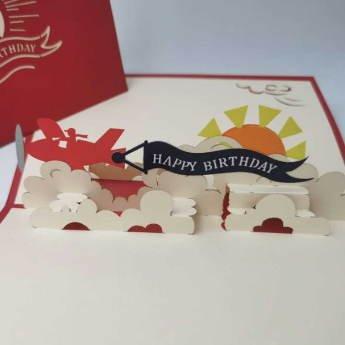 open pop up card with sun red plane clouds and happy birthday banner
