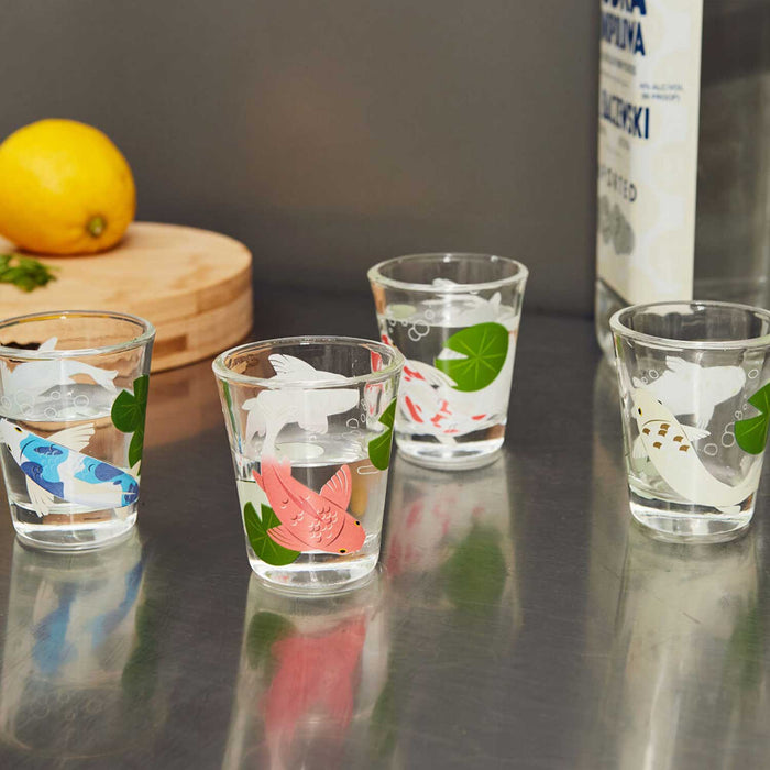 FOUR SMALL SHOT GLASSES WITH FISH PATTERN AND LEMMON AND VODKA BOTTLE IN THE BACKGROUND
