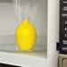 lemon shaped kitchen tool with holes in top sitting in an open microwave, emitting steam from the holes