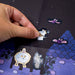 Hand placing a sticker of a ghost on a dark background with other stickers of ghosts and bats.