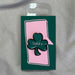 green shamrock pin with Lucky in white lettering in centre and black edge around shamrock