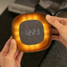 Lumos Clock, a square dark walnut wood clock with grey fabric digital clock face. The wooden frame of the clock is illuminated from behind the clock face. The clock is being held in someone's hands