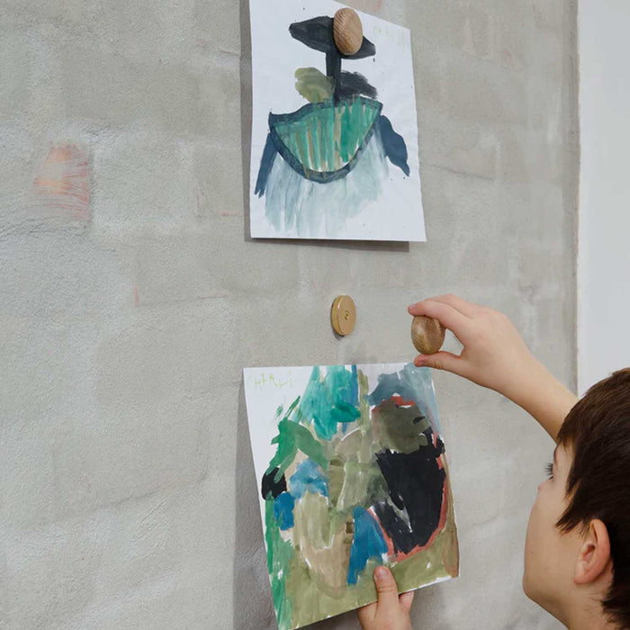 Child placing a painted  on a textured wall with a magnetic oak dot