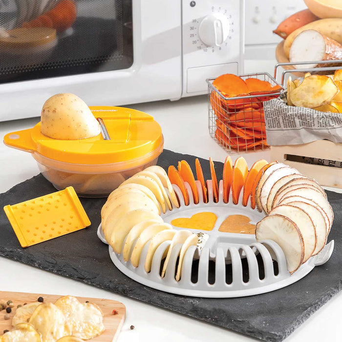 slices of potato and orange sweet potato standing in a white plastic ring with love heart shaped dip holders in cntre. Behind ring chip maker is a slicing mandolin with orange lid 