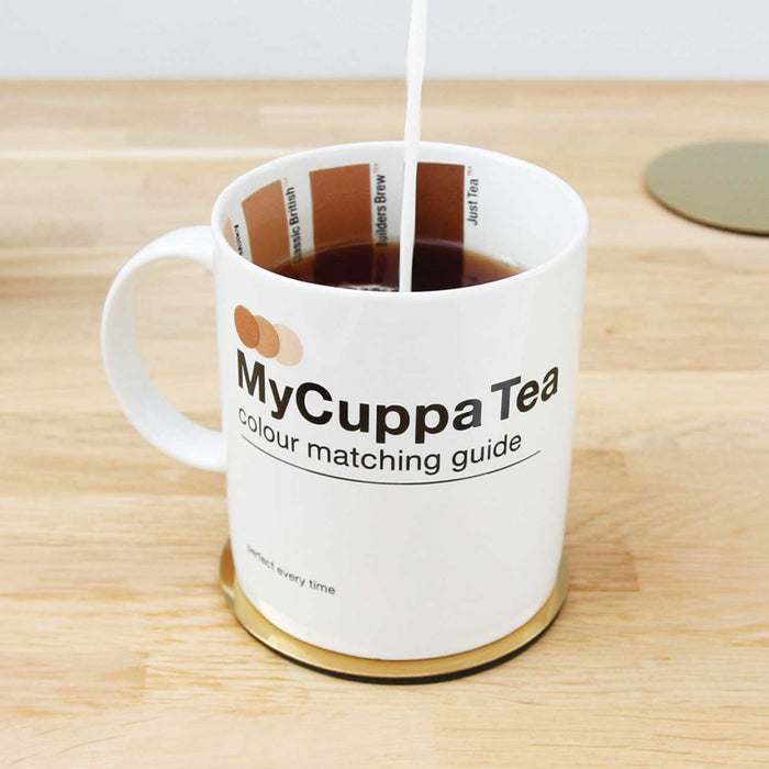 white tea cup with black tea and milk pouring in. Tea cup has 3 brown swatches of different shades on inside of mug and My Cuppa Tea in black text on outside of mug