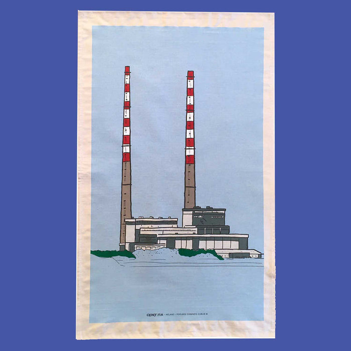 blue tea towel with white boarder and print of a low grey building with two red and white striped long chimney towers