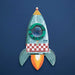 A cardboard rocket with a small kaleidoscopic window at the centre against a blue background.