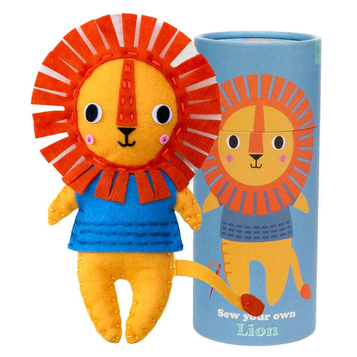 Plush lion toy with orange mane and blue outfit next to a cylindrical craft kit packaging on a white background.