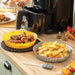 Silicone Airfryer Baskets & Brush set, one yellow round basket with cooked chicken wings and one grey basket with cooked chips on a counter top with black airfryer in background and grey bristle silicone brush in foreground