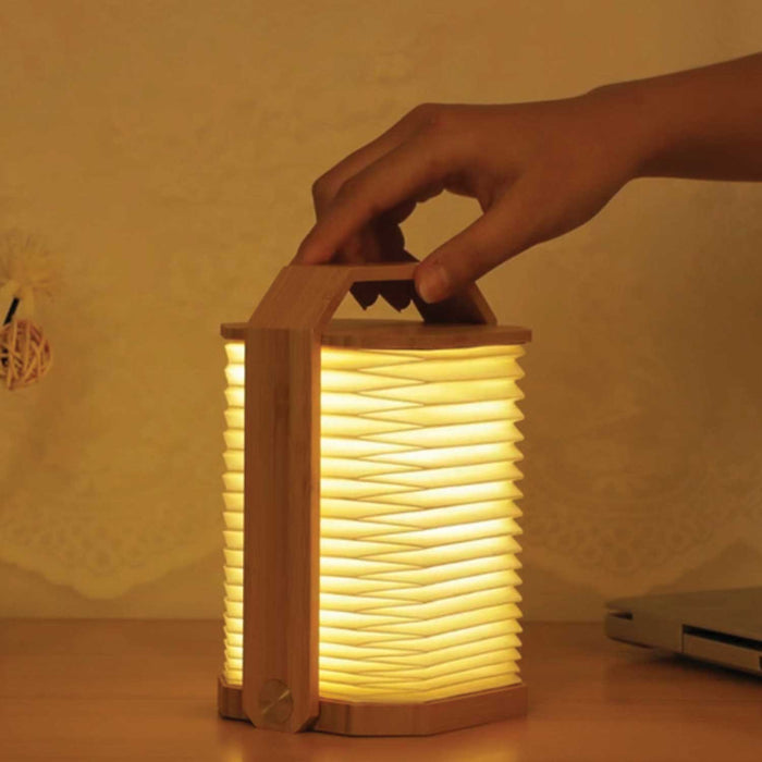 hold holding an illuminated paper and light wood origami lantern