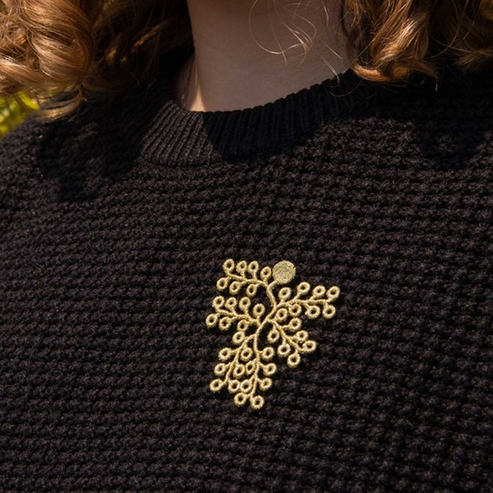 golden twig shaped brooch on a black knitted jumper