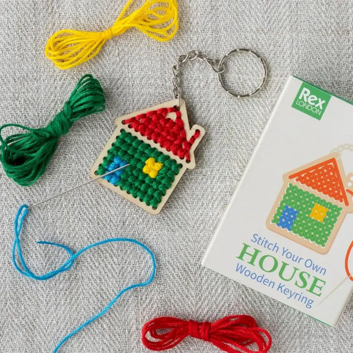 Stitch your own house wooden keyring kit with colorful threads and packaging on a textured surface.