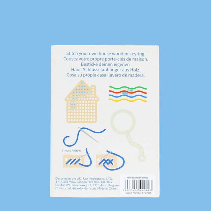 Package of wooden house keychains with sewing tools on a white background