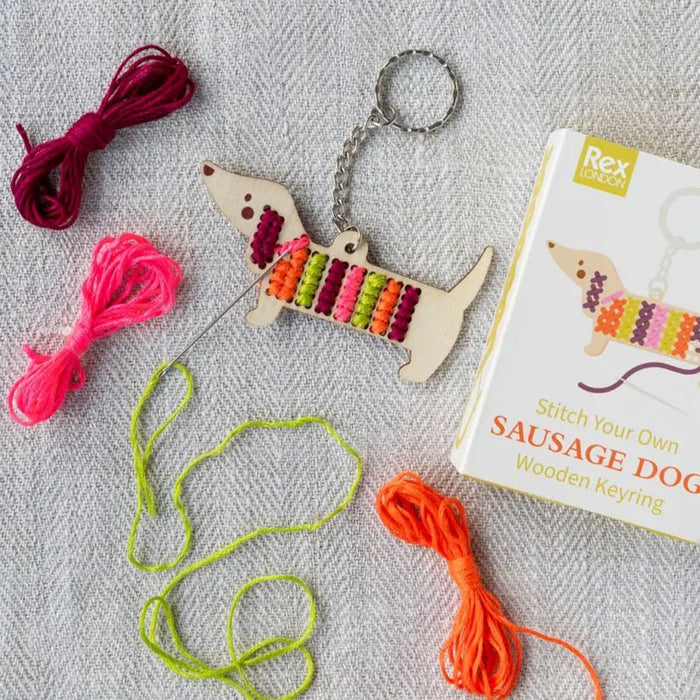 Sausage dog keyring with colorful embroidery floss and book on a textured surface