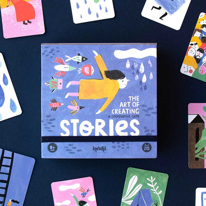 STORIES BOARDGAME BOX, BLUE WITHFLYING GIRL IN YELLOW JUMPER ON FRONT. GAME IS SURROUNDED BY ILLUSTRATED CARDS
