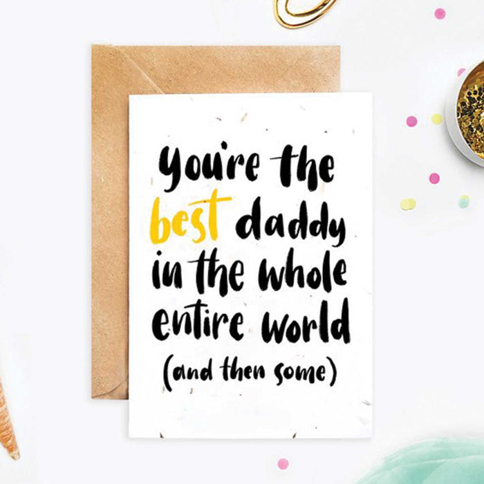 daddy white card with black text and best in gold text in front of brown envelop with speckled background 