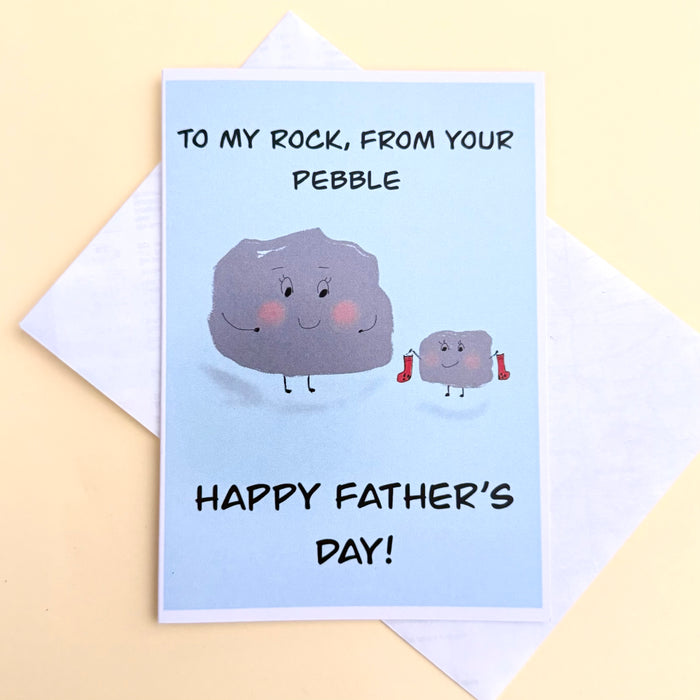 To mY Rock from Your Pebble Happy Father's Day card. blue card with white boarder and image of a little pebble gifting a red pair of socks to a larger smilng rock