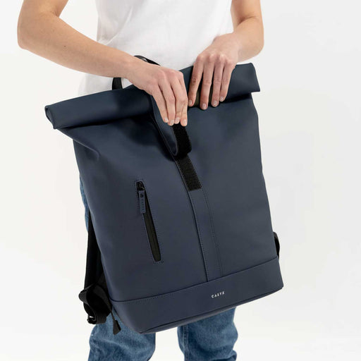 man holing a blue backpack with velcro strip closer in front of torso