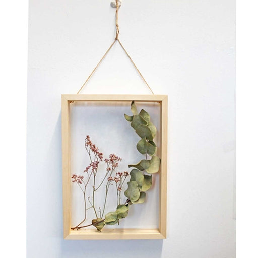 transparent wooden frame hanging from twine with foliage in frame