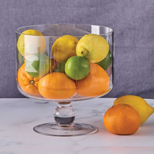 straight sided circular glass bowl with glass stand, filled with lemons, limes and oranages