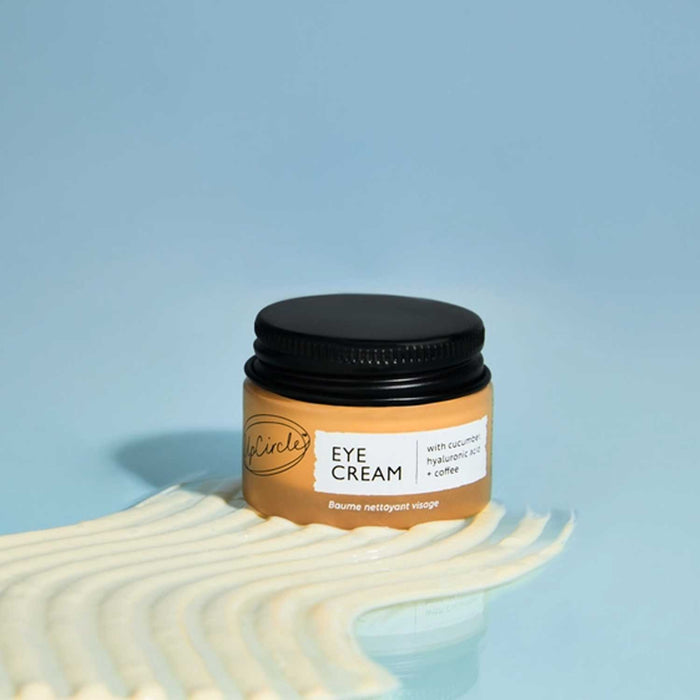 Jar of eye cream with a black lid on a blue background