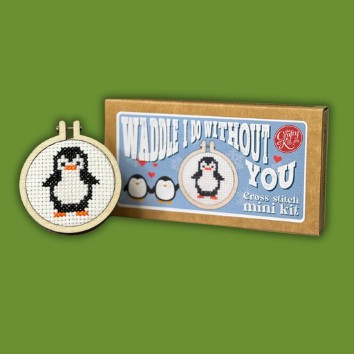 Cross-stitch mini kit with penguin design and packaging on a green background