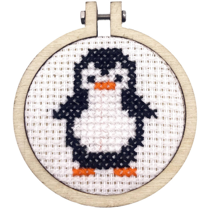 Cross-stitched penguin in a wooden hoop on a white background